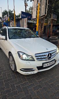 A white Mercedes-Benz C-Class parked outside the workshop in daylight