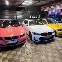 A pink BMW, a white BMW and a yellow BMW parked together inside the workshop at night
