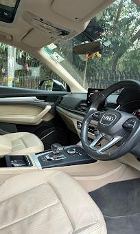 The interior of an Audi Q5 showing the steering wheel, dashboard and cream leather seats