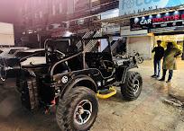A modified black off-road vehicle parked outside the workshop at night