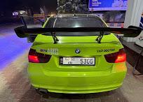 The rear of a lime green BMW M3 with a large rear spoiler, photographed at night